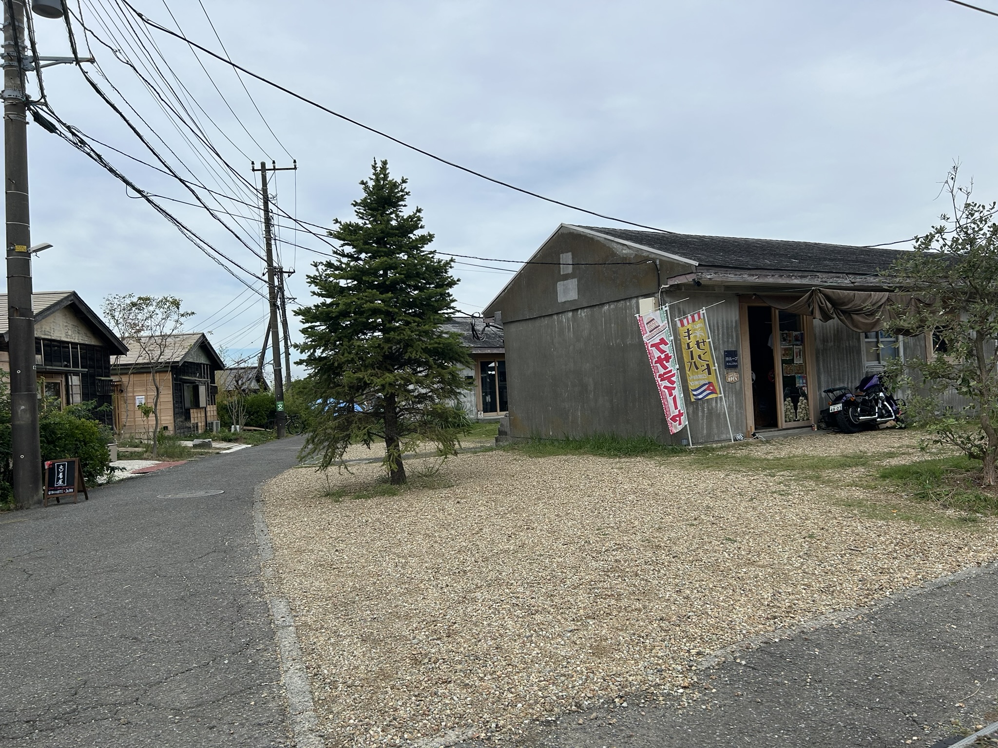月見台住宅の長屋通りと砂利の広場。再生された平屋が店舗兼用で並ぶ風景